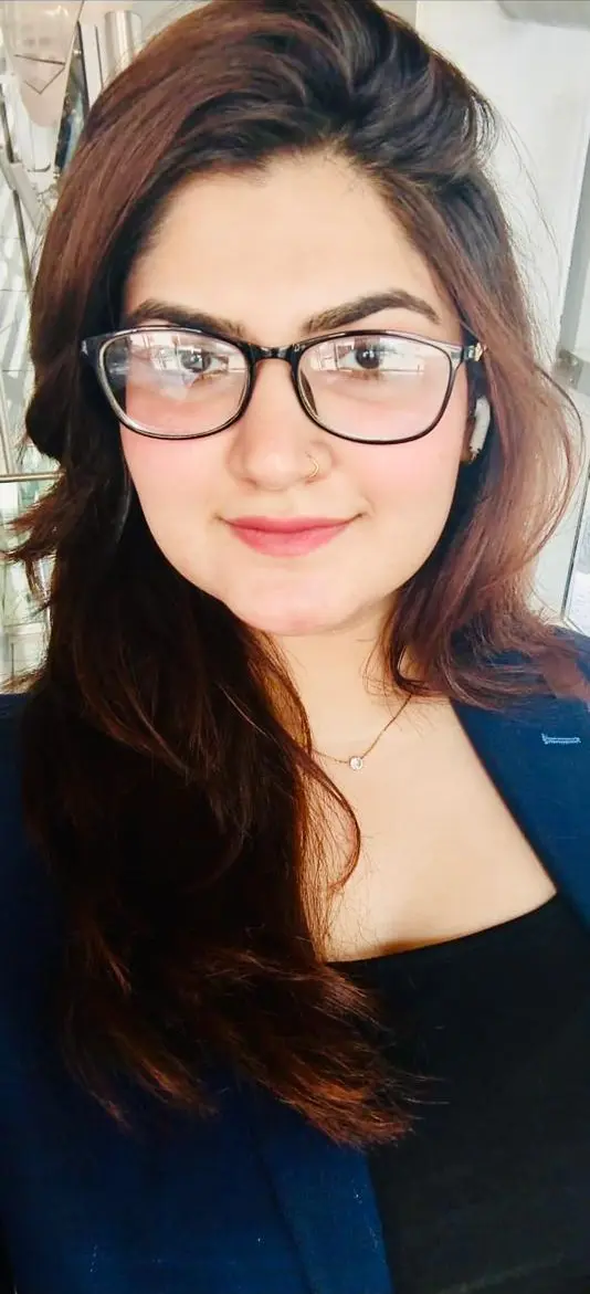 Portrait of Harsha Devi wearing glasses and a navy blazer