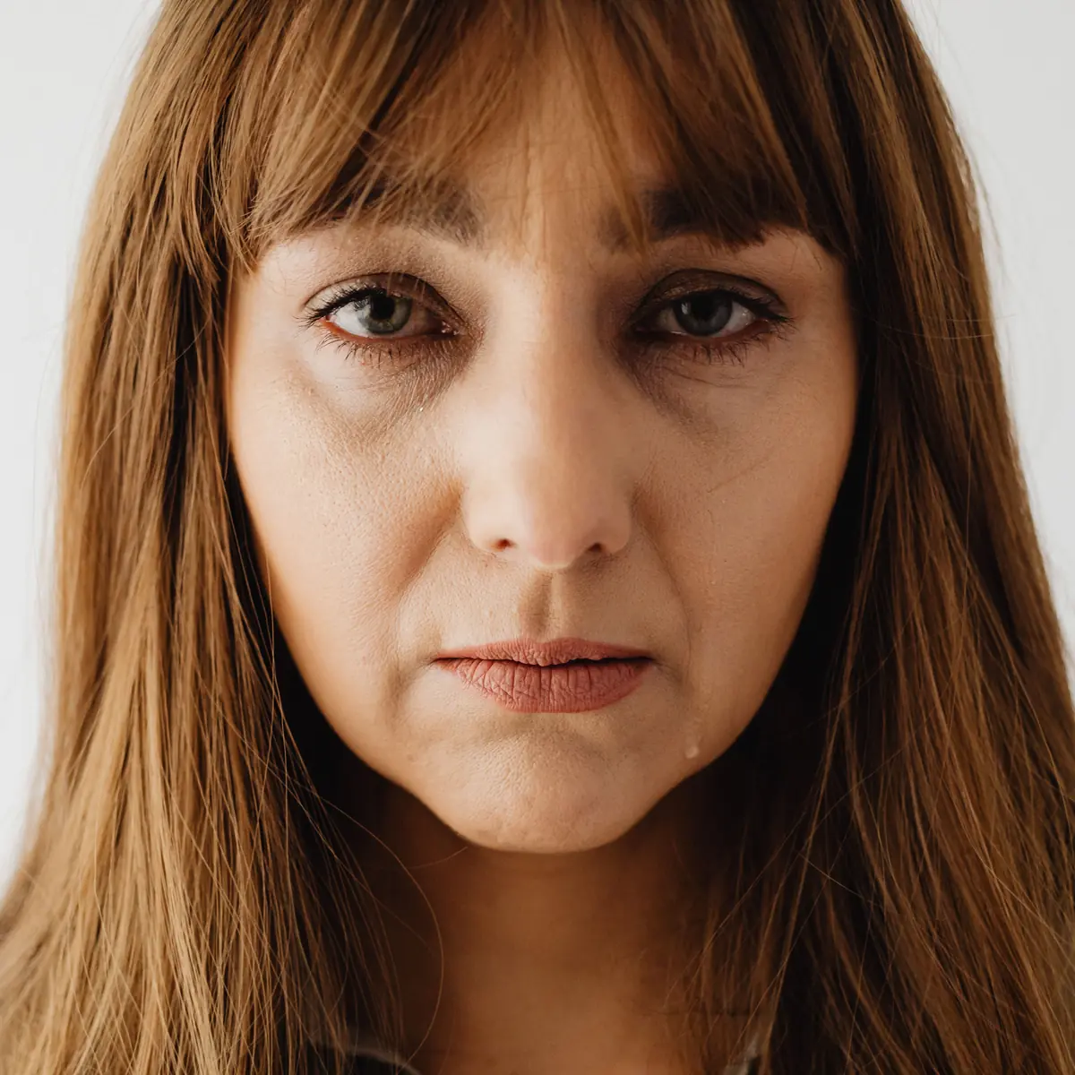 A woman looking directly into the camera, serious and questioning